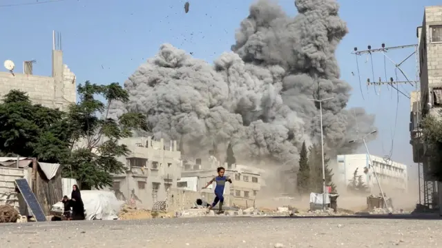 Bir kız çocuğu,  İsrail'in Gazze'nin merkezindeki Bureyc Mülteci Kampı'ndaki yerlerinden edilmiş kişilerin sığındığı bir okula düzenlediği hava saldırısından kaçıyor (17 Temmuz 2025)