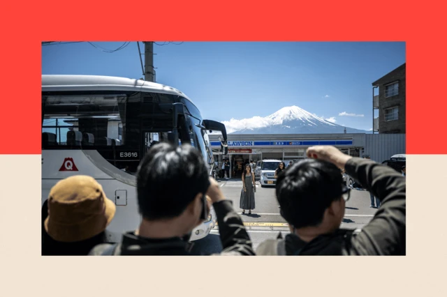 Turistler 3 Mayıs 2024 tarihinde bir marketin karşı sokağından Fuji Dağı ile fotoğraf çektiriyor.