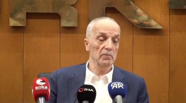 Ergün Atalay basın toplantısında konuşuyor, önünde üç tane mikrofon var