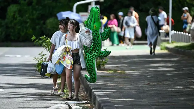 Japonya'daki Chiba şehrinde bulunan Tokyo Bay'de halk sahil bölgelerinden ayrılıyor, iki kadın ellerinde şişme deniz yataklarını taşıyor