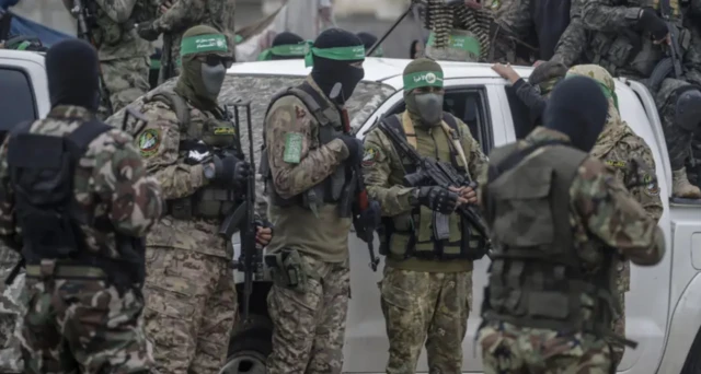 Hamas militanları yüzlerini de kapatan üniformalar ve silahlar içinde görünüyor
